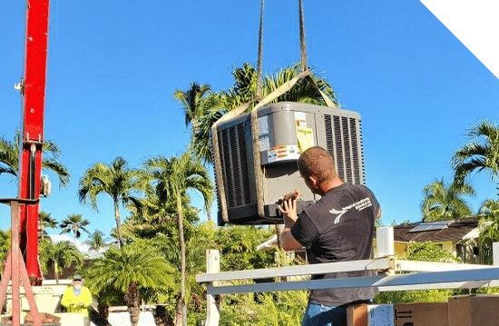 A man is lifting a large air conditioning unit during Maui HVAC services.