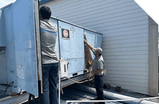 Two men providing Maui Hvac Services on an air conditioning unit.