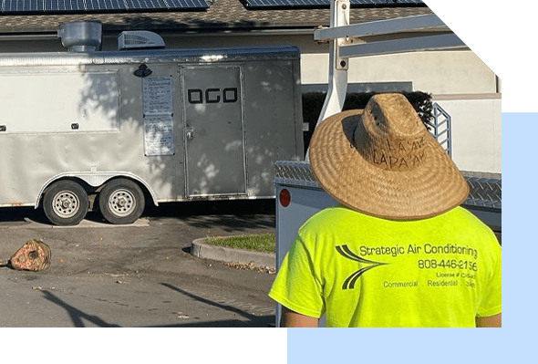 A man in a yellow shirt is standing next to a solar trailer, showcasing the Strategic Air Conditioning system.